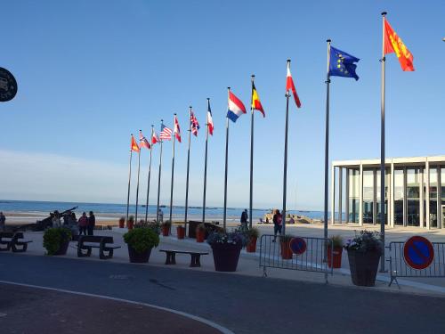 Une bande de drapeaux devant une plage dans l'établissement Le Cocon de Neptune, à Arromanches-les-Bains