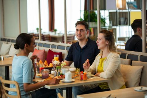 拉姆朗的住宿－IntercityHotel Zürich Airport，坐在餐厅桌子上的男人和女人