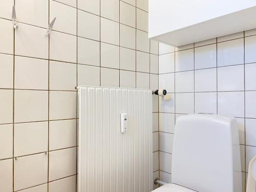 a bathroom with a toilet and a white tiled wall at One Bedroom Apartment In Valby, Langagervej 64, in Copenhagen
