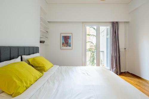 una camera da letto bianca con un grande letto bianco con cuscini gialli di Spacious Central Apt Downtown ad Atene
