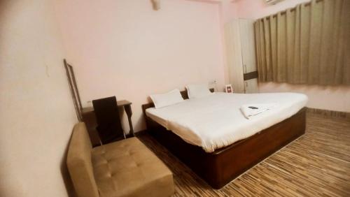 a bedroom with a bed and a chair in it at hotel darbar international in Gaya