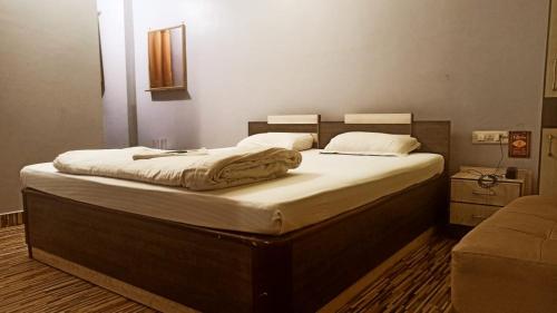 a bedroom with a large bed with white sheets at hotel darbar international in Gaya