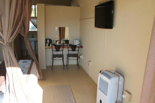 Zimmer mit einem TV und einem Tisch mit Stühlen in der Unterkunft Pyramids Motel in Van Reenen