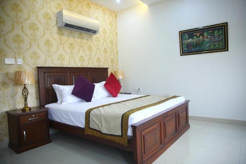 una camera da letto con un letto con lenzuola bianche e cuscini viola di Gulberg Suites a Lahore
