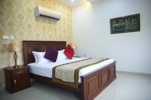 a bedroom with a bed with white sheets and purple pillows at Gulberg Suites in Lahore