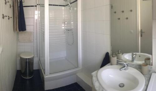 a white bathroom with a sink and a shower at Au Tour Des Bois in Le Vésinet