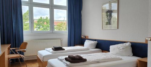 a hotel room with two beds and a window at HW Hotel - Haus am Niederfeld in Berlin