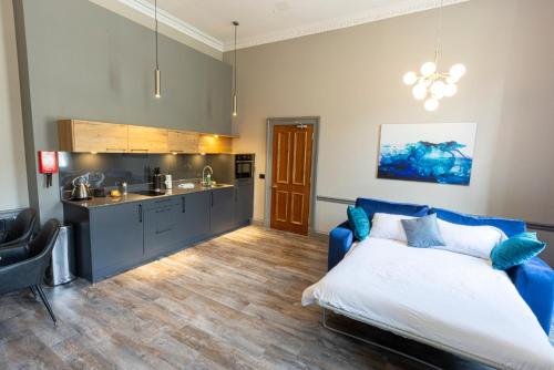 a bedroom with a blue bed and a kitchen at MONO Suites NEW TOWN in Edinburgh