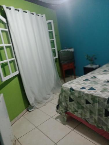 a bedroom with a bed and a white curtain at Mel Pousada in Macaé