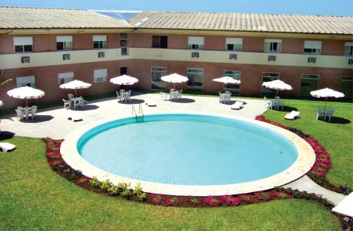 a large pool in front of a building with umbrellas at Hotel Sambura in Imbé