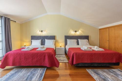 two beds in a room with two red sheets at flowers island house 4 in Caniço