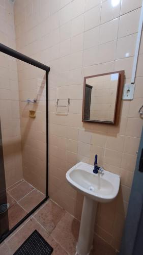 a bathroom with a sink and a shower with a mirror at Temporada no Paraíso in Ilha Comprida