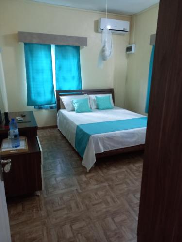 a bedroom with a large bed with blue curtains at Island Breeze in Mahébourg