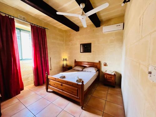 um quarto com uma cama e uma ventoinha de tecto em Ta’ Guża Farmhouse em Tal-Barmil