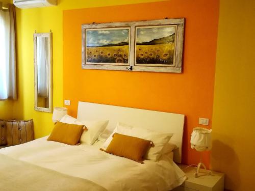 um quarto com uma cama branca e uma parede laranja em Agriturismo La Dependance em Sorano