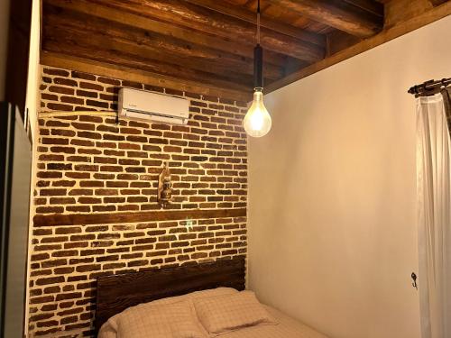 una camera con un muro di mattoni, un letto e una luce di Karga Butik Otel a Diyarbakır