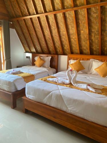 two beds with swans on them in a bedroom at Wani Bali Bungalow in Nusa Penida