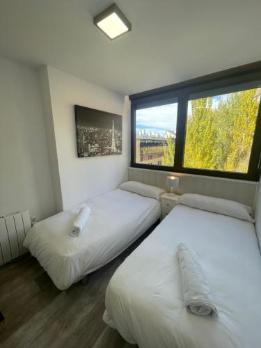 two beds in a room with a large window at Apartamento Ski Place 6 personas in Sierra Nevada