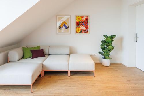 a living room with two white couches and a plant at POHA House Theaterplatz in Aachen