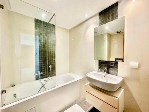 Baño blanco con lavabo, bañera y espejo en Elyssa superbe appartement aux Jardins de Carthage, en Cartago