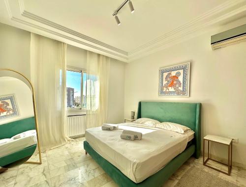1 dormitorio con 1 cama con cabecero verde y espejo en Elyssa superbe appartement aux Jardins de Carthage, en Cartago
