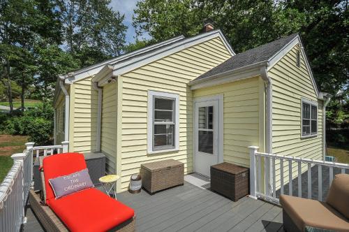 a small yellow house with a red chair on a deck at House Near Bju, Furman, & Town in Greenville
