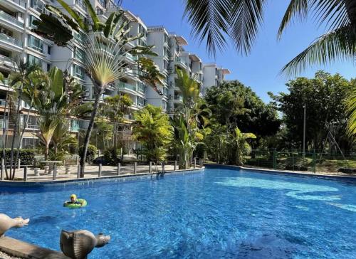 a large swimming pool with palm trees and a building at Sunny Apartment, minutes to beach in Shuijiao