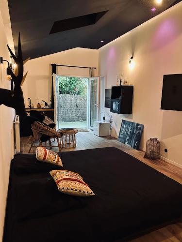 - une chambre avec un lit noir et un salon dans l'établissement Apt 35 m2 Baignoire Balnéo terrasse privée, à Amfreville-la-Mi-Voie