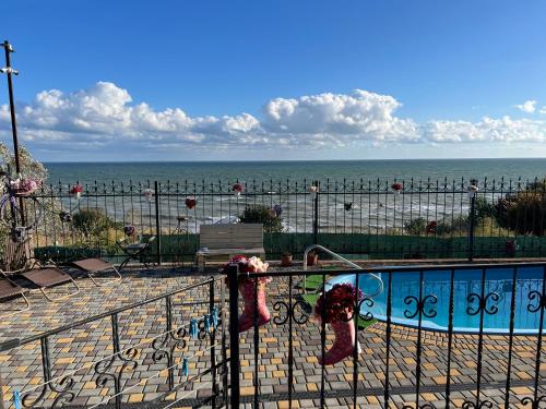 a fence with a pool and the ocean in the background at Flower Breeze in Chebanka