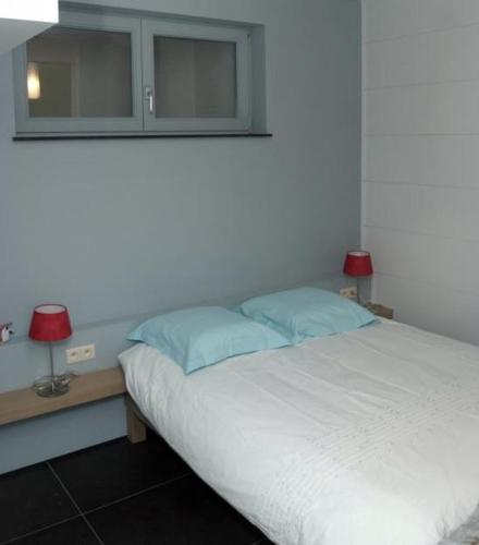 a bedroom with a bed with two lamps and a mirror at Amalia, ontspannen aan zee in Oostduinkerke in Oostduinkerke