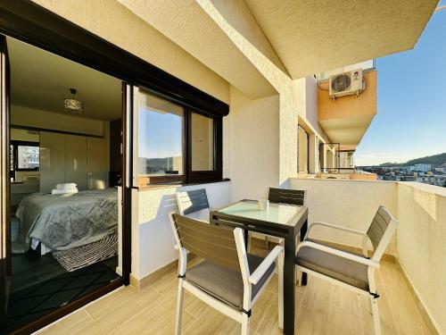 een klein balkon met een tafel en stoelen en een bed bij Adria Apartment in Râmnicu Vâlcea