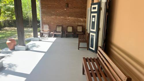 a porch with benches and a door with a brick wall at Honey Tree Polonnaruwa in Polonnaruwa