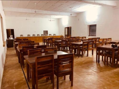 een leeg klaslokaal met houten tafels en stoelen bij Lakhina Heritage desert camp in Jaisalmer