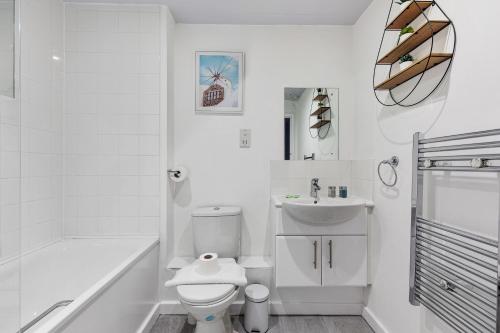 a white bathroom with a toilet and a sink at King's Cross Cabin in London