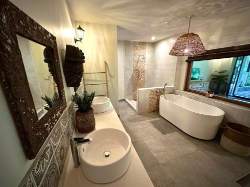 uma casa de banho com uma banheira, um lavatório, uma banheira e um espelho. em Sakae Paradise Resort em Lusaka