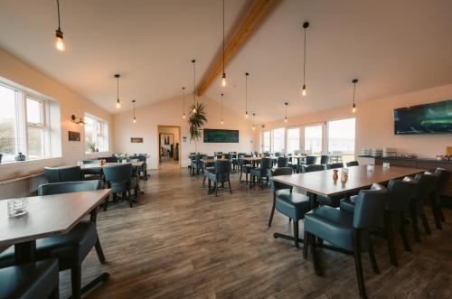 uma sala de jantar com mesas, cadeiras e janelas em Hotel Vos em Hella
