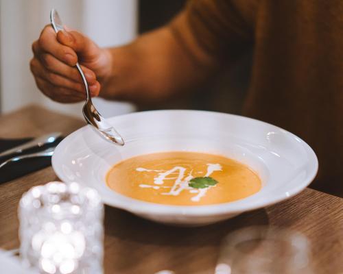 a person eating a bowl of soup with a spoon at Hotel Vos in Hella