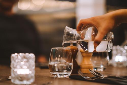 a person pouring water into a glass on a table at Hotel Vos in Hella