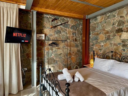 a bed in a room with a stone wall at Fikardou Chalets in Phikardhou