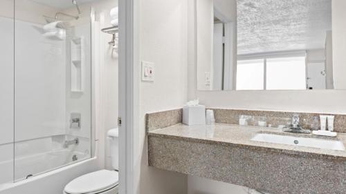 a bathroom with a sink and a toilet and a mirror at Baymont by Wyndham Jacksonville Airport in Jacksonville