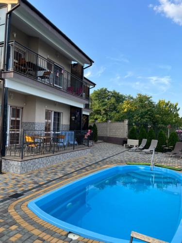 uma grande piscina azul em frente a uma casa em Flower Breeze em Chebanka