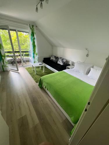 - une chambre avec un lit vert et un canapé dans l'établissement Plitvice Studio Sara, aux lacs de Plitvice