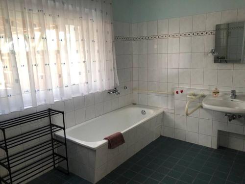 een witte badkamer met een bad en een wastafel bij Haus in Weisen 