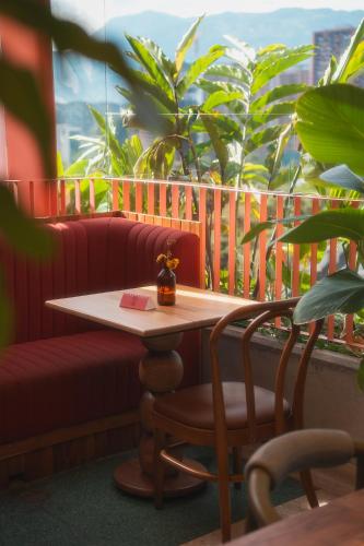 a table and a chair on a balcony with plants at The Somos Bold Hotel in Medellín