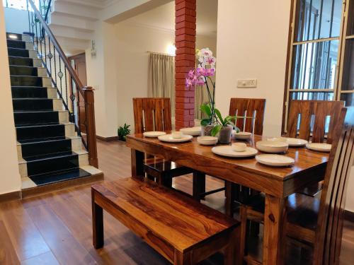 uma sala de jantar com uma mesa de madeira e cadeiras em The Rustic Manor - Homestay em Bangalore