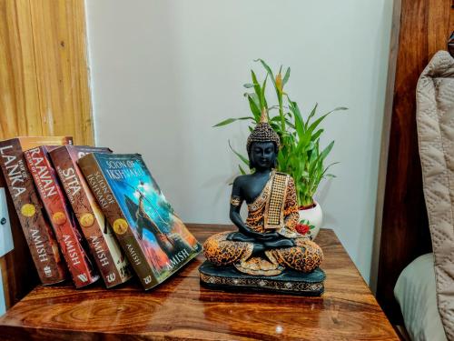 a table with books and a buddha statue on it at The Rustic Manor - Homestay in Bengaluru