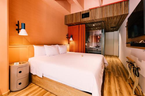 a bedroom with a large white bed and a kitchen at The Somos Bold Hotel in Medellín