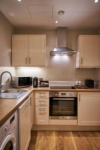 a kitchen with white cabinets and a stove top oven at The Capital Hotel, Apartments & Townhouse - Small Luxury Hotels of The World in London