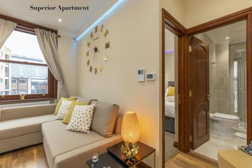 a living room with a couch and a clock on the wall at Stylish Apartment Kensington in London