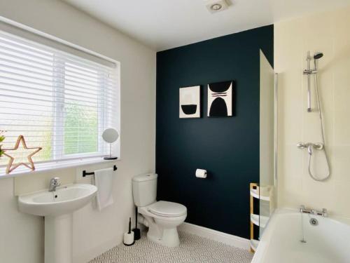 a bathroom with a white toilet and a blue wall at uSnooz I Charming 4-Bed Halifax Home with Garden in Halifax